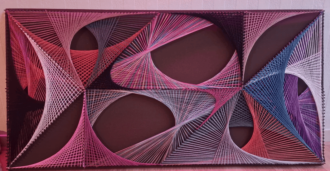 String art composition featuring intersecting arcs and geometric shapes, created with pink, purple, red, and blue threads arranged on a rectangular frame to form a dynamic abstract design.